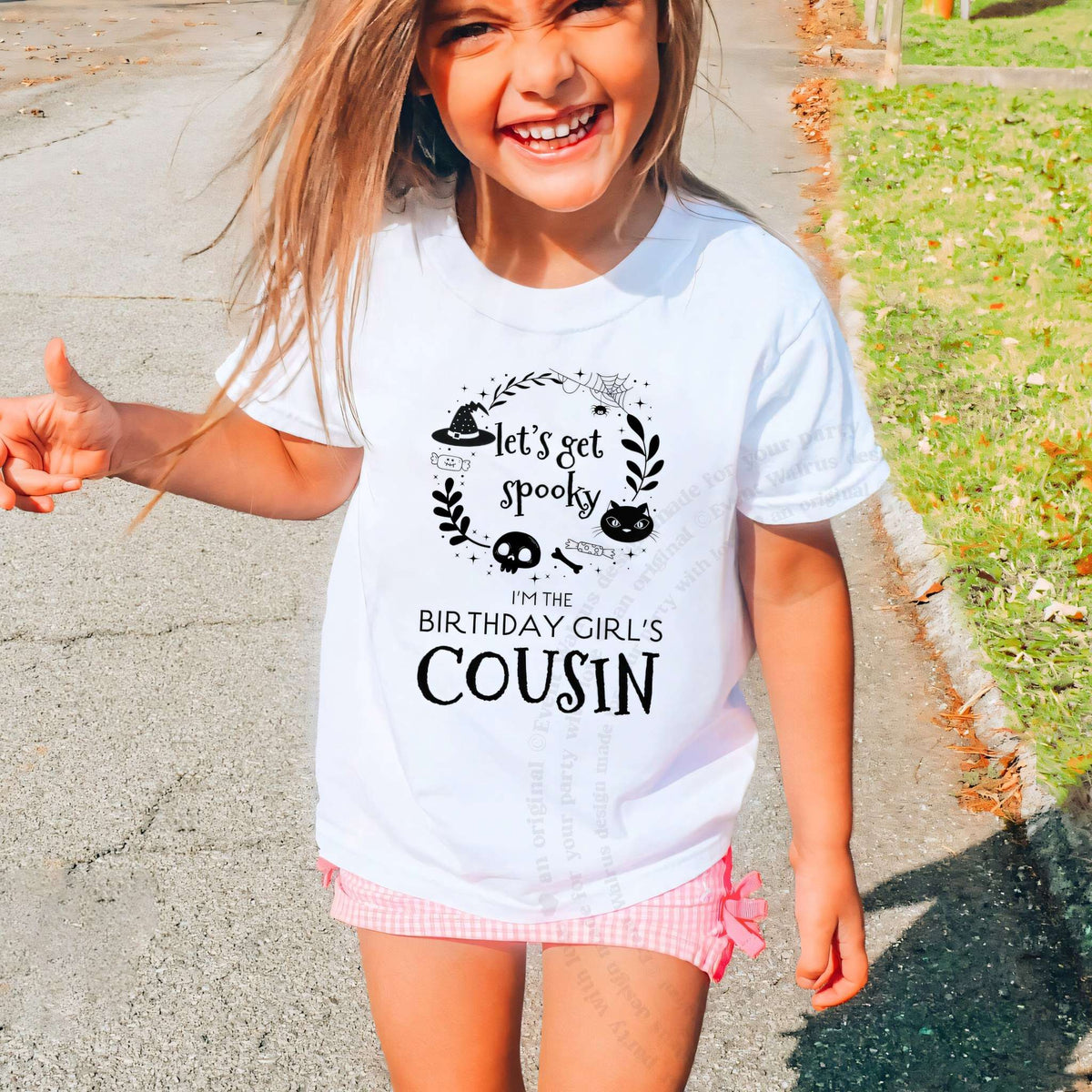 Laughing girl outdoors in a white Let's Get Spooky Cousin kids tee.