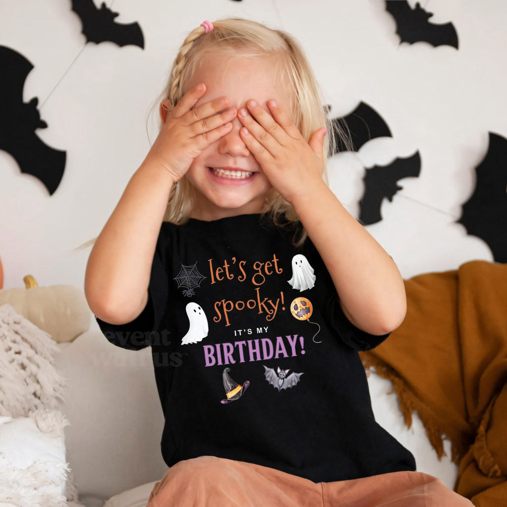 Girl covering her eyes in a black Let's Get Spooky It's My Birthday shirt by paper bats.
