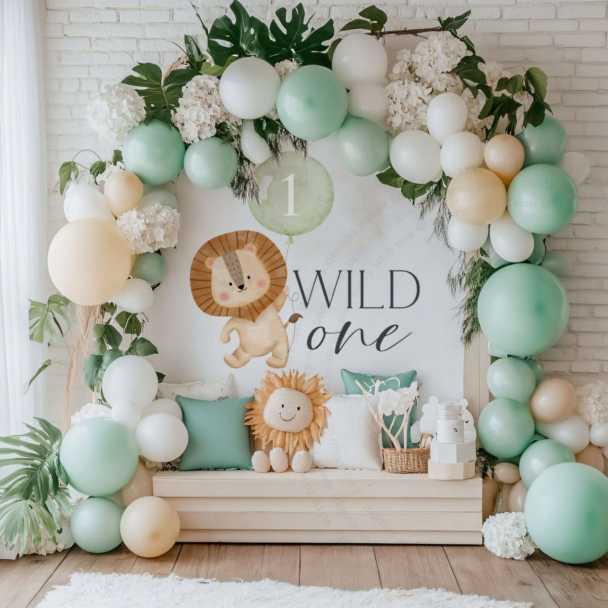 Lion Wild One banner indoors against white brick with a mint balloon arch, palm leaves and a lion pillow.
