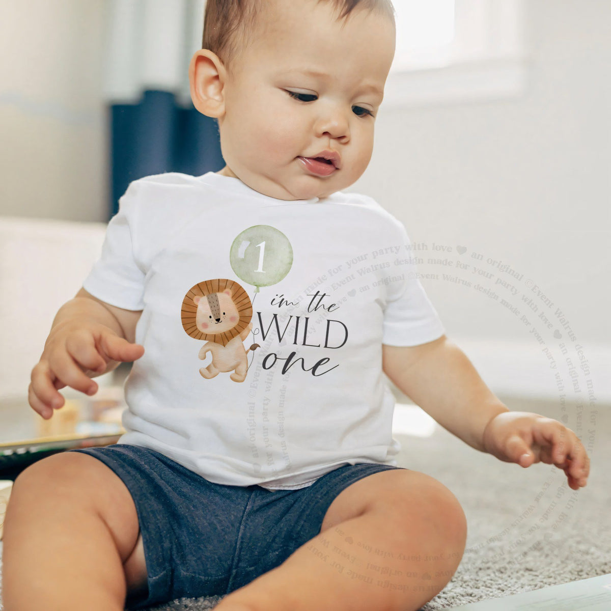 Baby boy sitting on a rug in a white I'm the Wild One baby tee.
