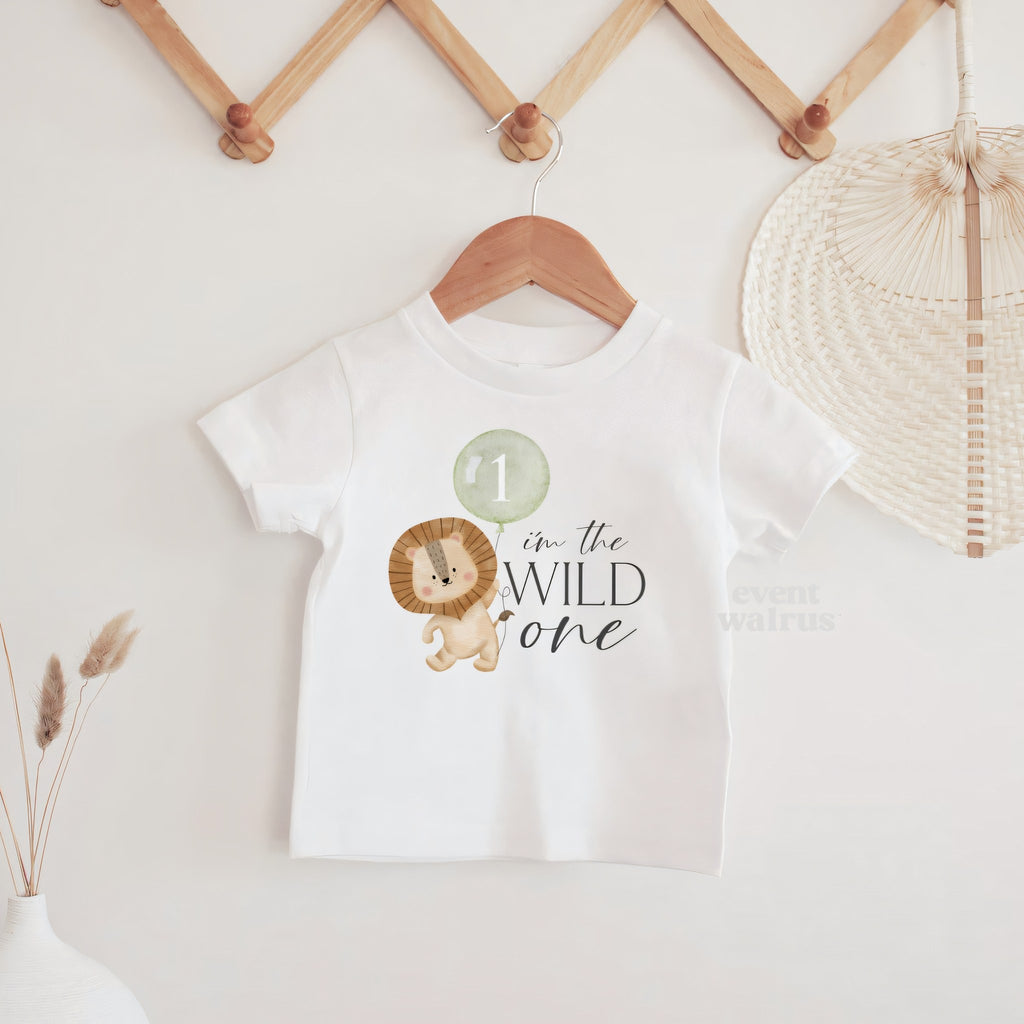 White I'm the Wild One baby tee hanging on a wooden peg rail.