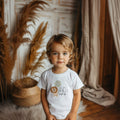 Toddler birthday boy in a white I'm the Wild One tee with the lion and sage balloon.