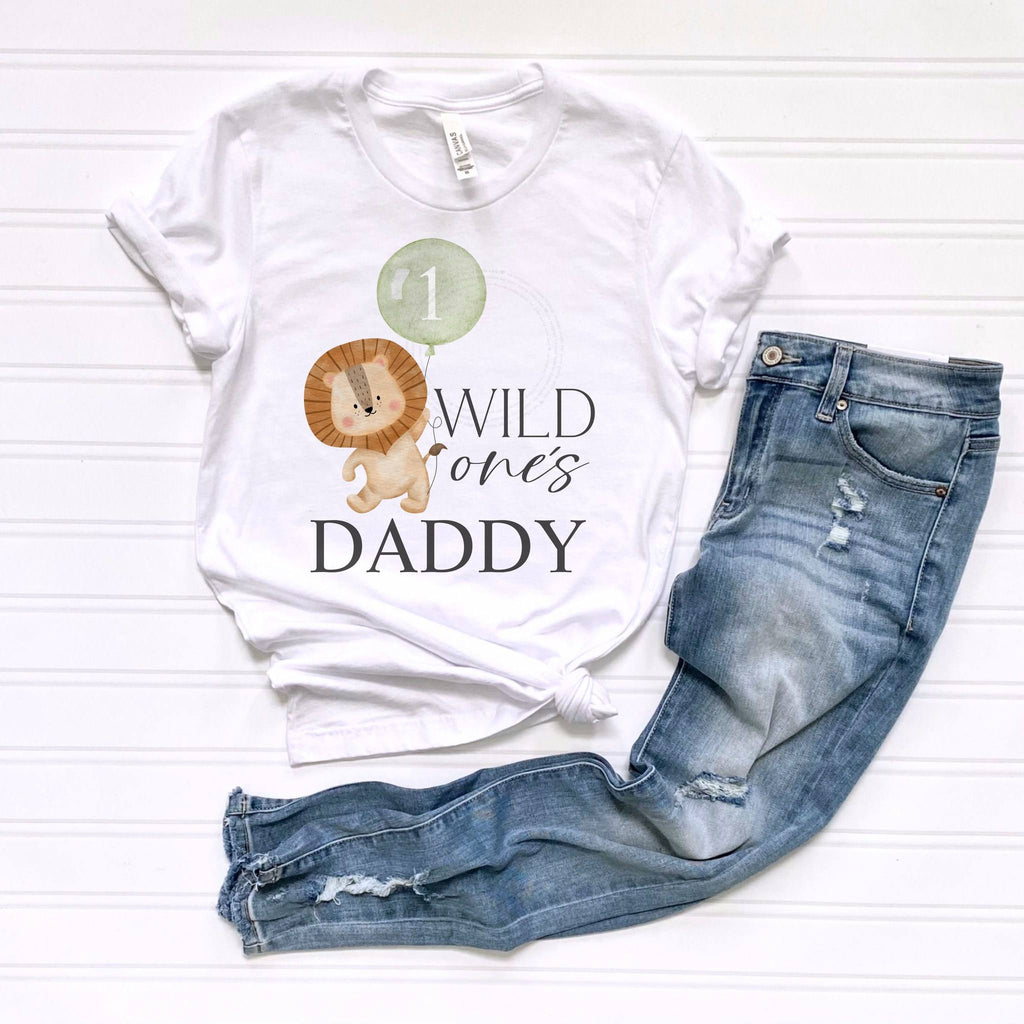 White Wild One's Daddy adult tee laid flat beside ripped jeans.