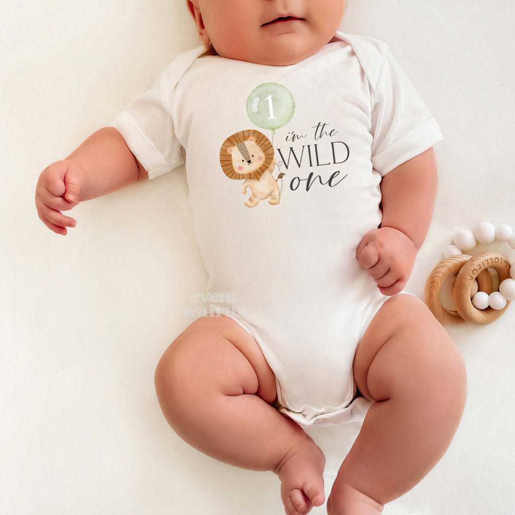 Baby lying on a white blanket in an I'm the Wild One bodysuit with the lion and sage balloon.