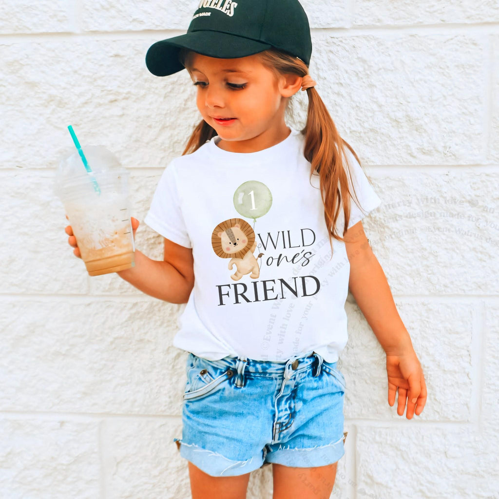 Girl in a ball cap holding a drink in a white Wild One's Friend shirt.