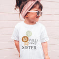 Girl in sunglasses and a pink headband wearing a white Wild One's Sister shirt with the lion design.