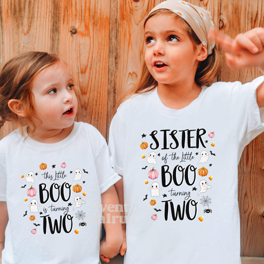 Birthday girl beside her big sister, both in white Little Boo Turning Two shirts.