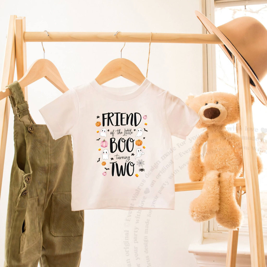 White Friend of the Little Boo toddler tee on a wooden clothes rack beside a teddy bear.