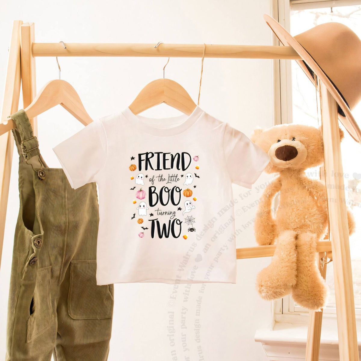 White Friend of the Little Boo toddler tee on a wooden clothes rack beside a teddy bear.