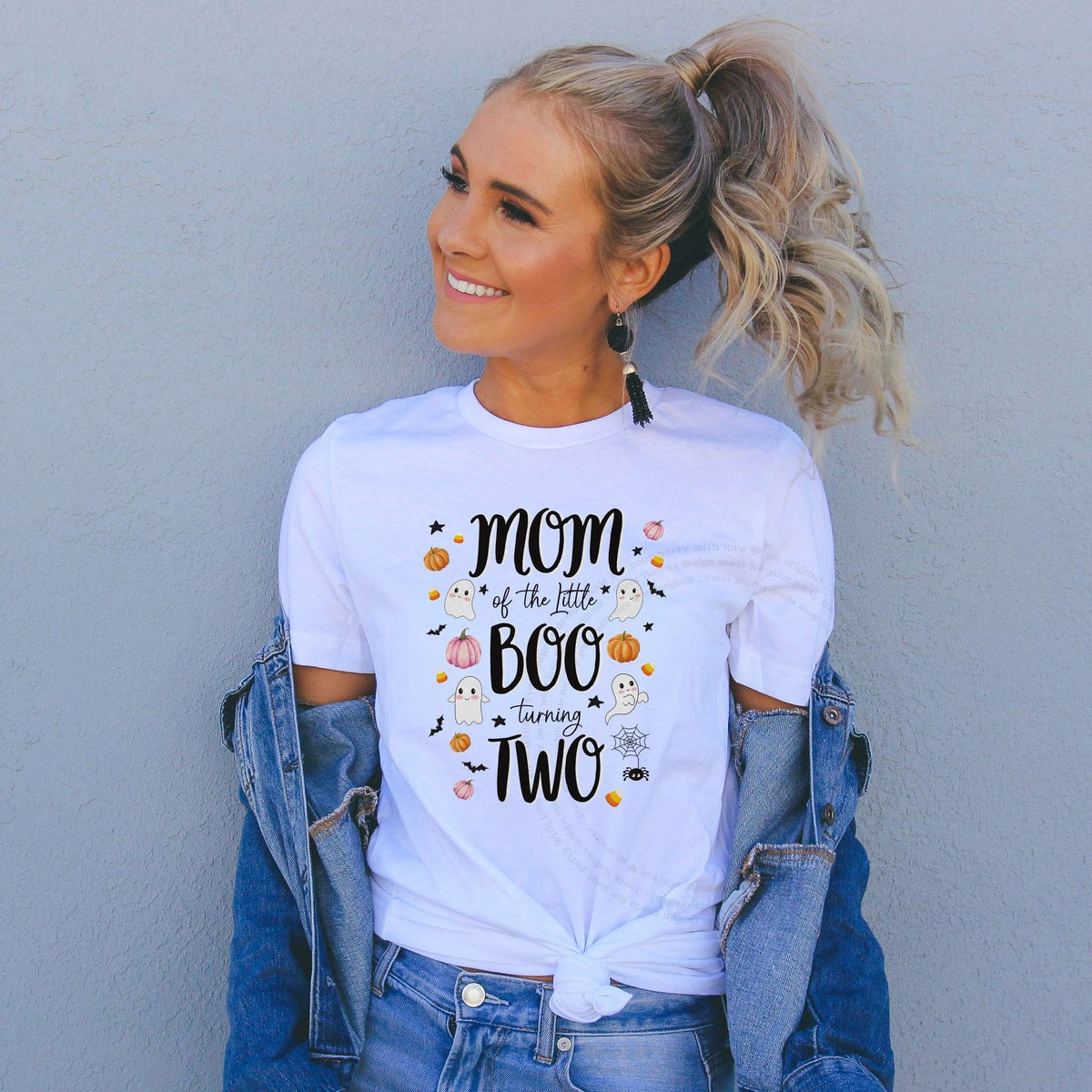 Woman in a denim jacket wearing a Mom of the Little Boo Turning Two shirt with ghosts.