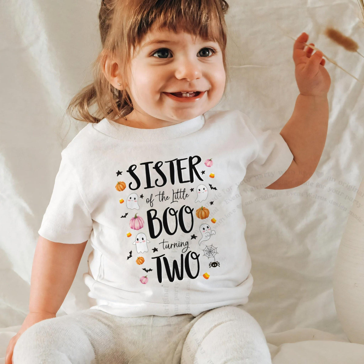 Laughing baby girl in a white Sister of the Little Boo baby tee.