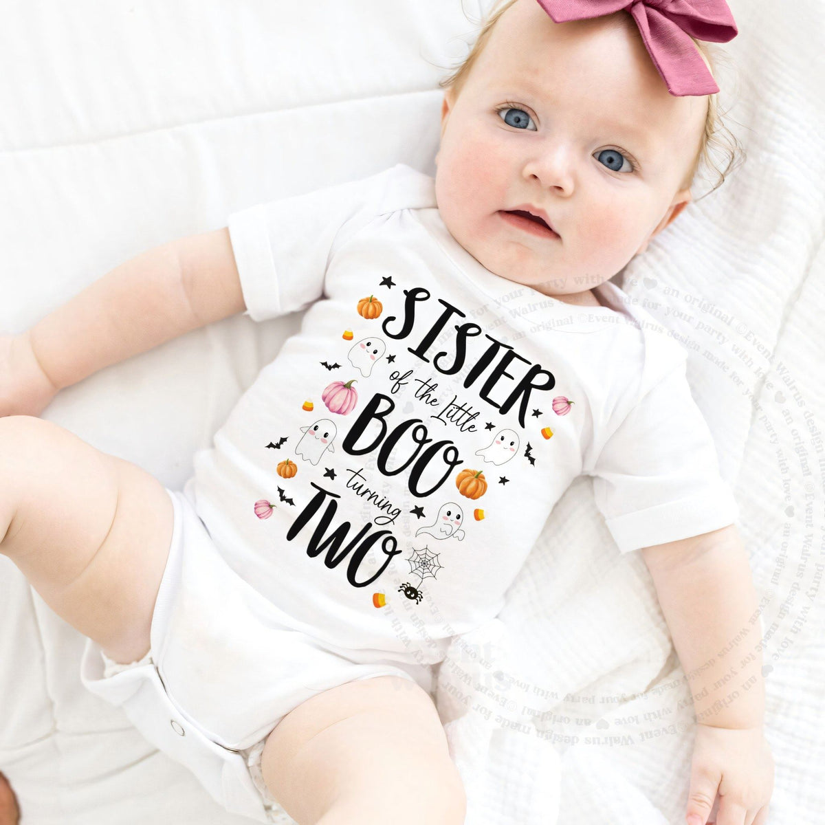Baby girl with a pink bow lying in a white Sister of the Little Boo bodysuit.