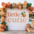 Little cutie backdrop by a pool with an orange, green and peach balloon garland.