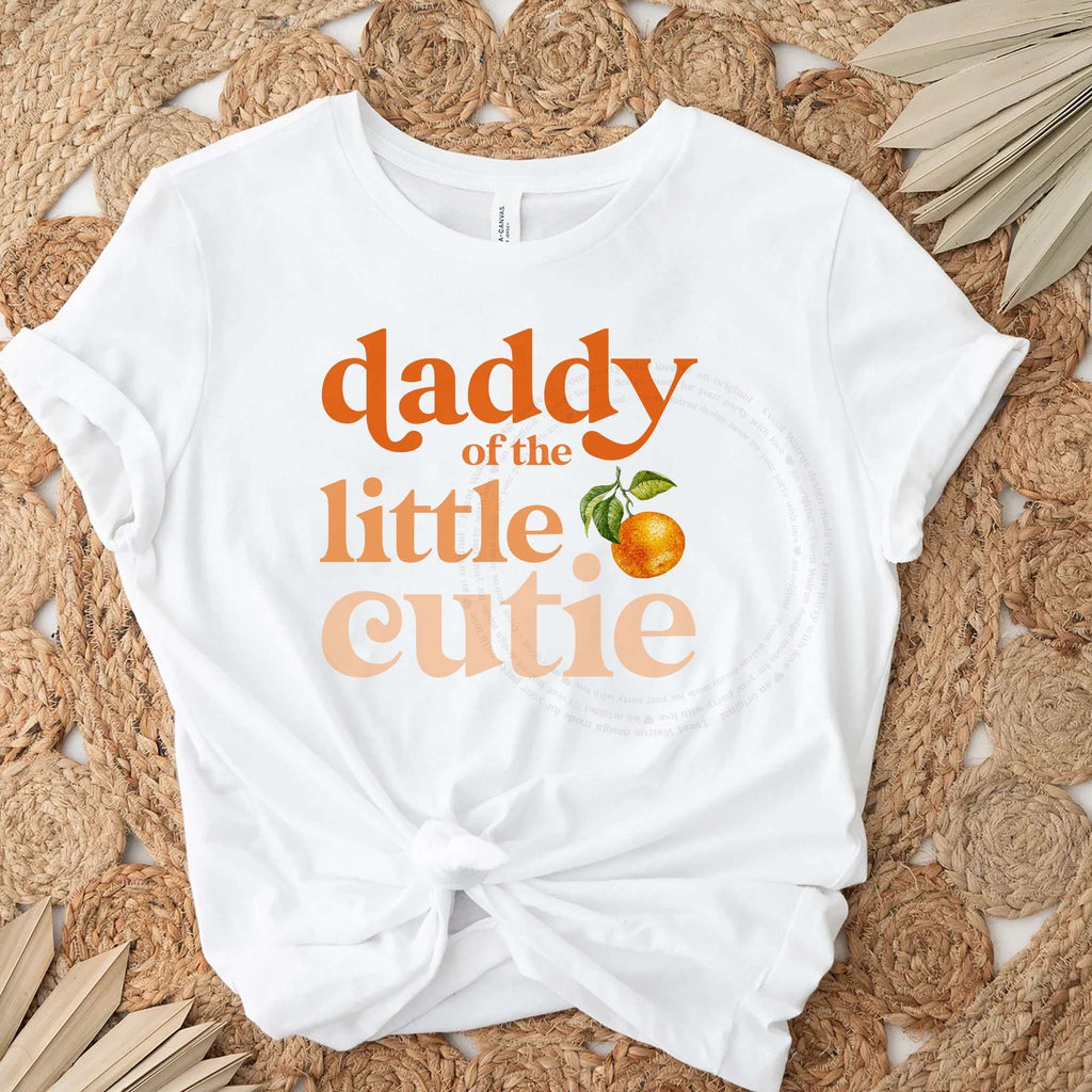 White Daddy of the Little Cutie tee knotted on a jute rug with dried palm leaves.