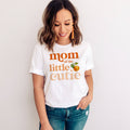 Smiling woman in jeans wearing a white Mom of the Little Cutie shirt with a watercolor clementine.