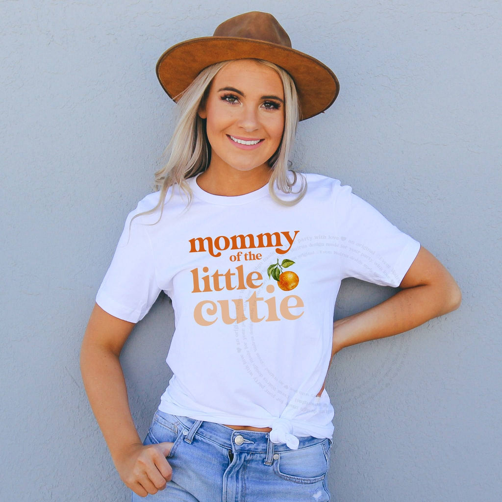 Woman in a brown hat wearing a white Mommy of the Little Cutie tee with orange lettering.