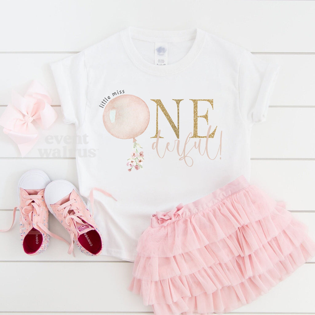 White Little Miss Onederful toddler tee laid flat with a pink tutu and pink sneakers.