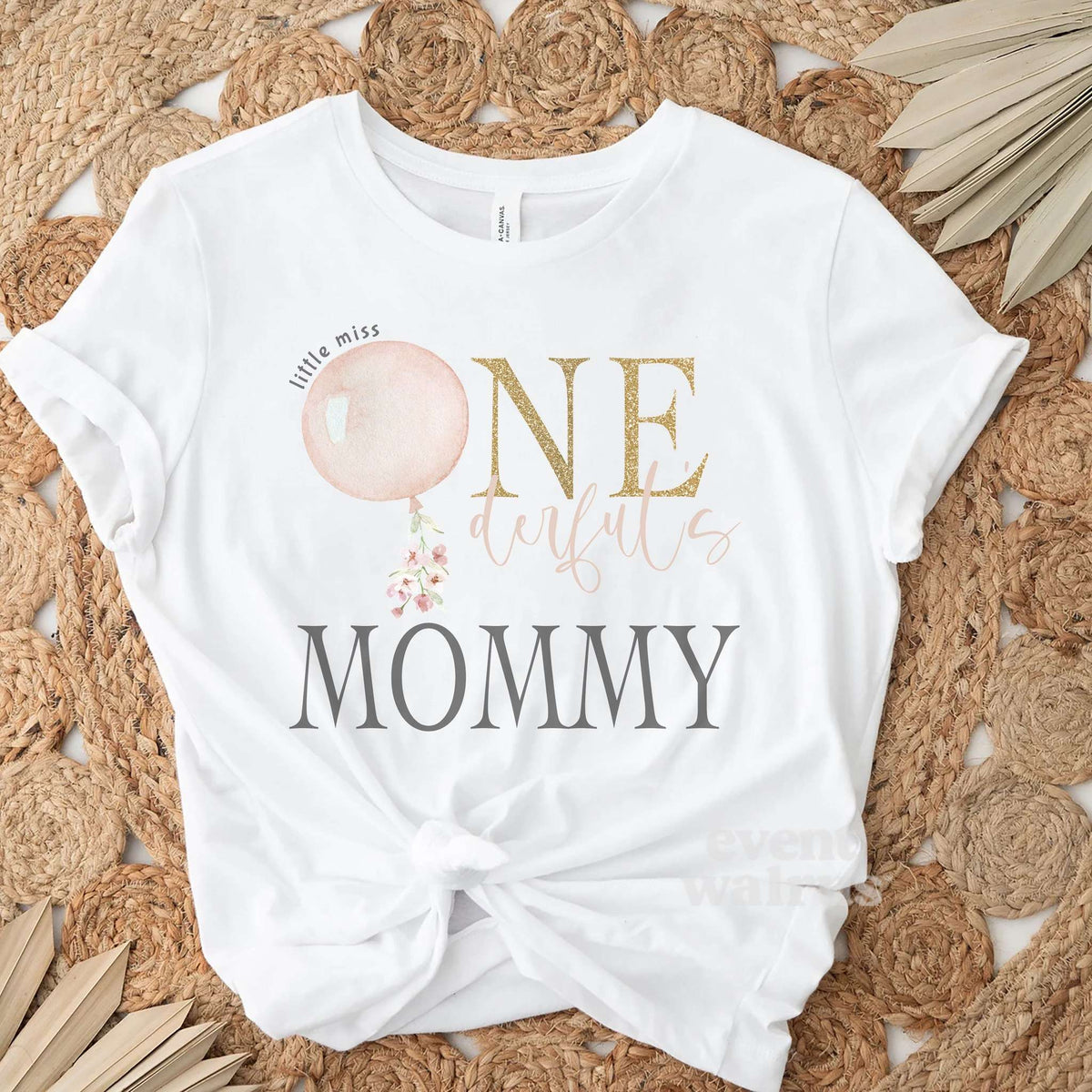 White Mommy Little Miss Onederful adult tee laid flat on a woven jute rug.