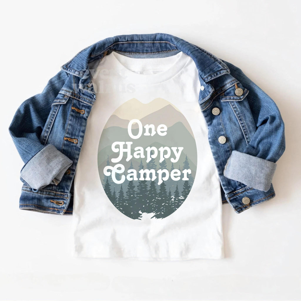 White One Happy Camper toddler tee laid on a denim jacket.