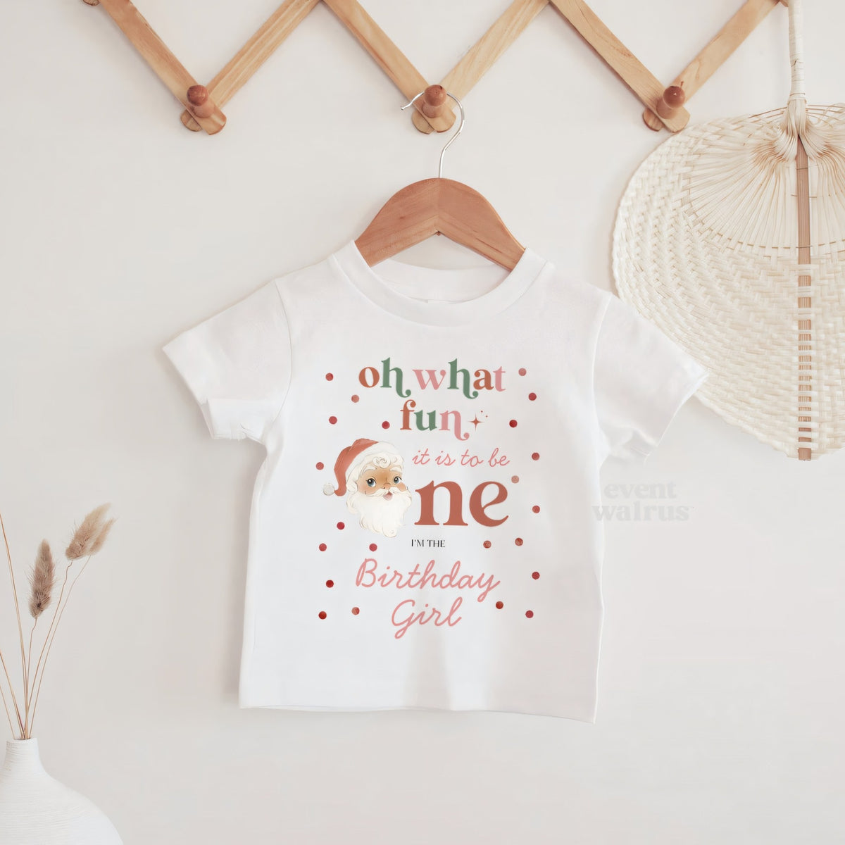 White Oh What Fun Birthday Girl baby tee hanging on a wooden peg rail.