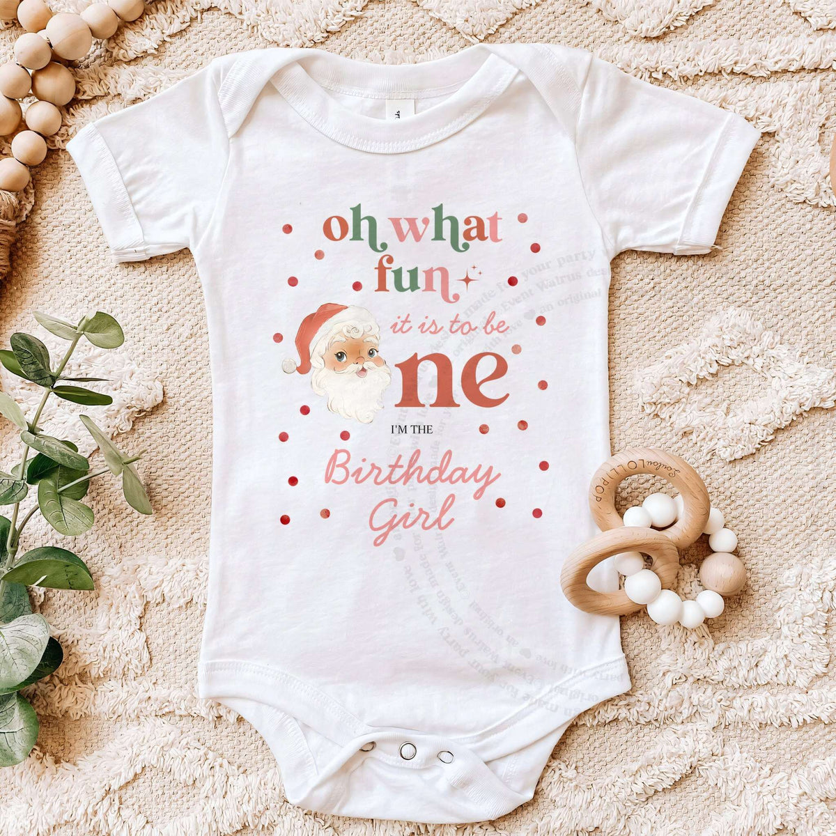 White Oh What Fun Birthday Girl bodysuit on a beige blanket with a wooden teether.