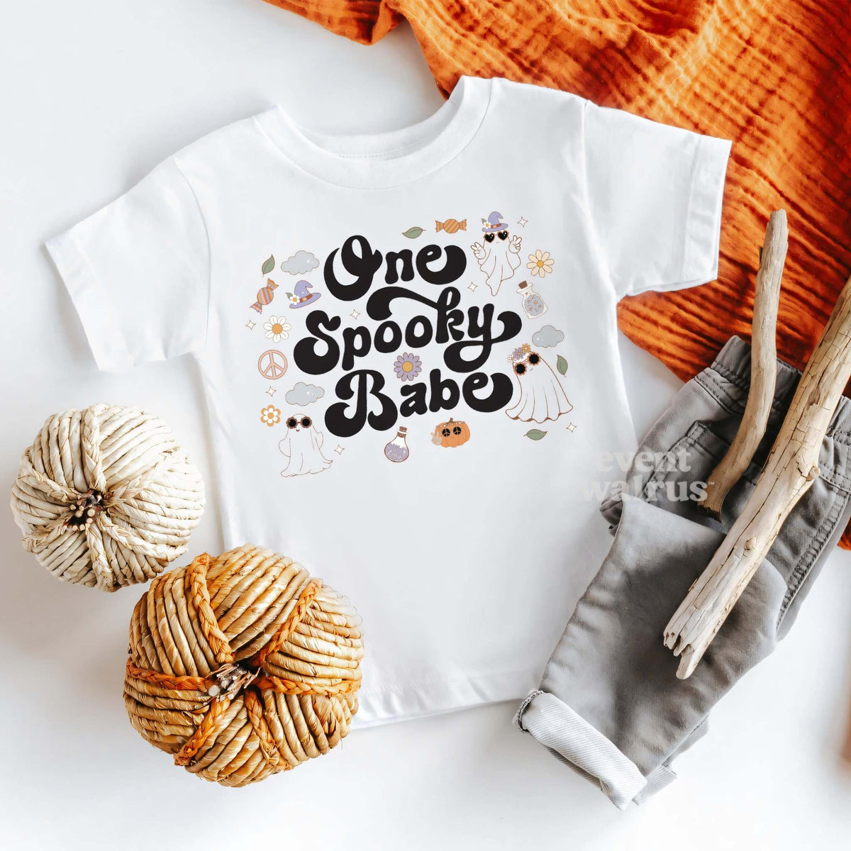 White One Spooky Babe baby tee laid flat with pumpkins and gray pants.
