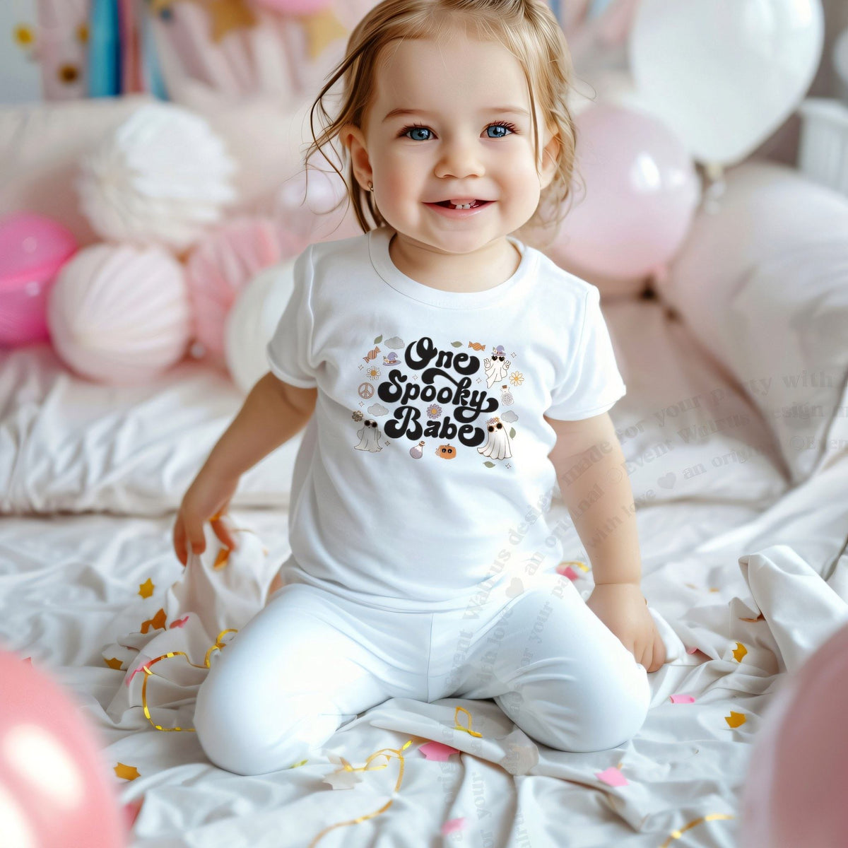 Smiling toddler girl among pink balloons in a white One Spooky Babe tee.
