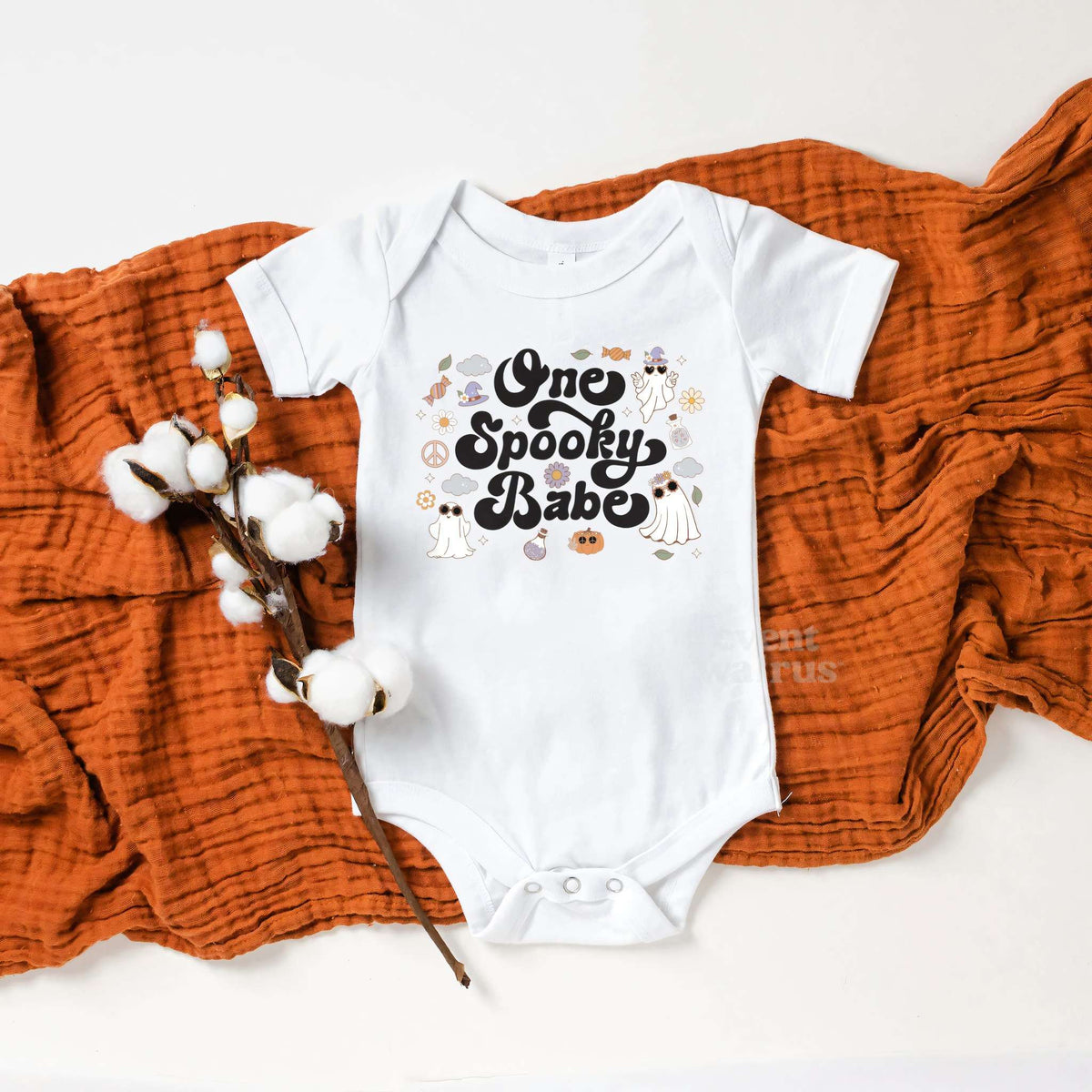 White One Spooky Babe bodysuit on a rust blanket with cotton stems.