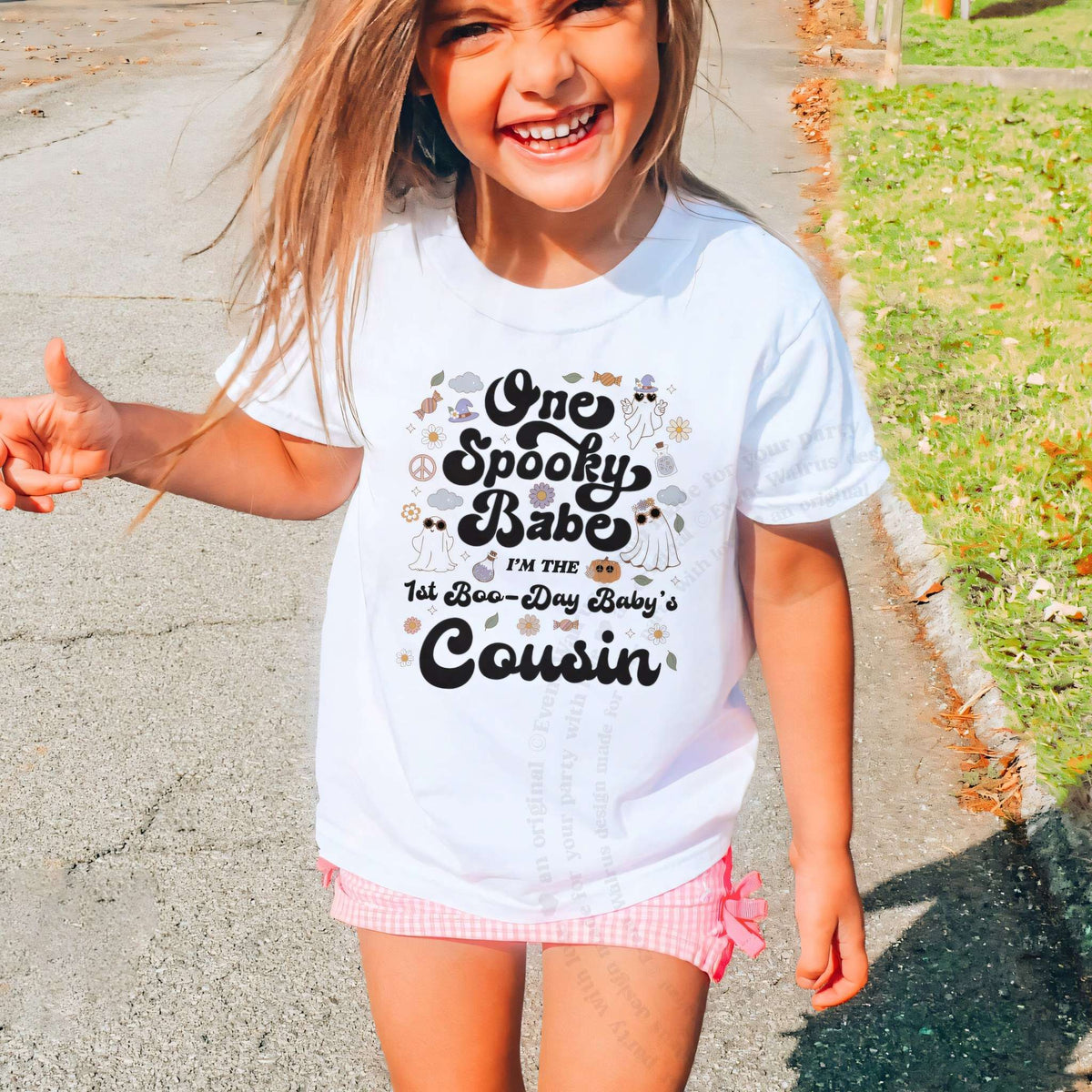 Laughing girl outdoors in a white One Spooky Babe Cousin kids tee.
