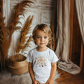 Toddler boy in a white I'm the Spooky One tee in orange script with friendly monsters.