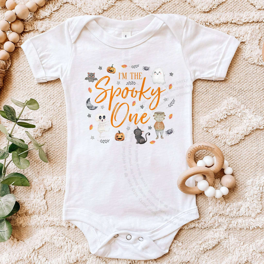 White I'm the Spooky One bodysuit on a beige blanket with a wooden teether.