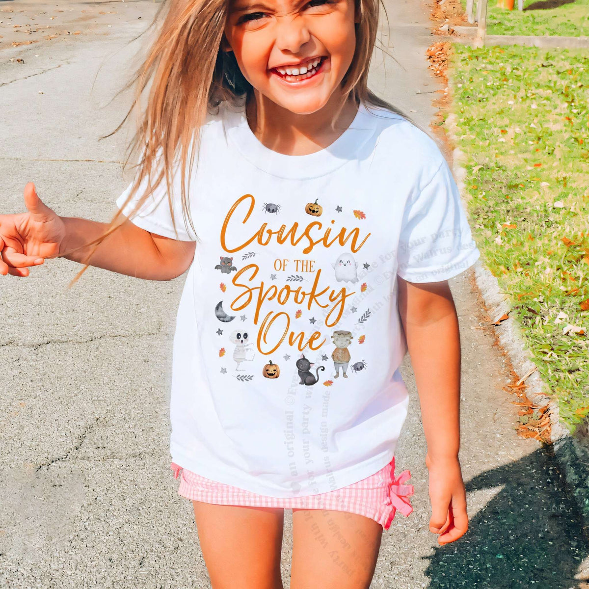 Laughing girl outdoors in a white Cousin of the Spooky One kids tee.