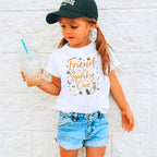 Girl in a ball cap holding a drink in a white Friend of the Spooky One shirt.