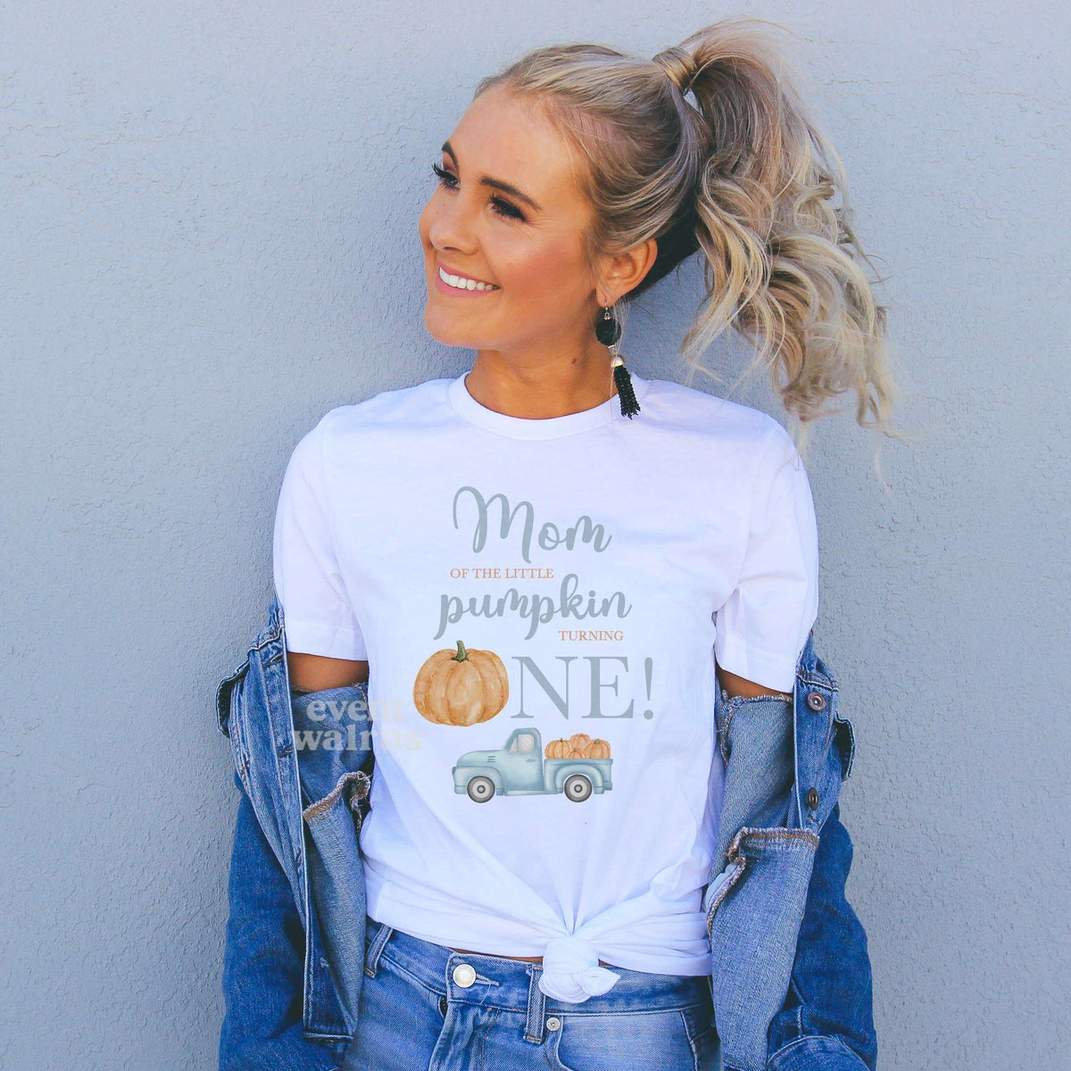 Woman in a denim jacket wearing a Mom of the Little Pumpkin shirt with a pale blue truck.