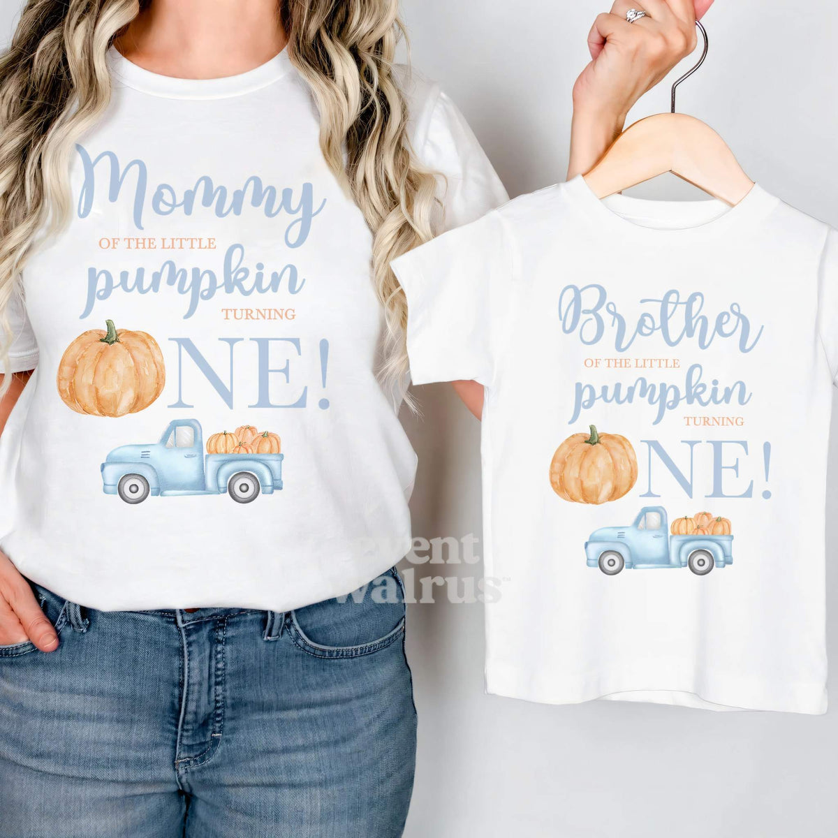 Mom in a white Mommy Little Pumpkin shirt holding up a matching Brother tee.