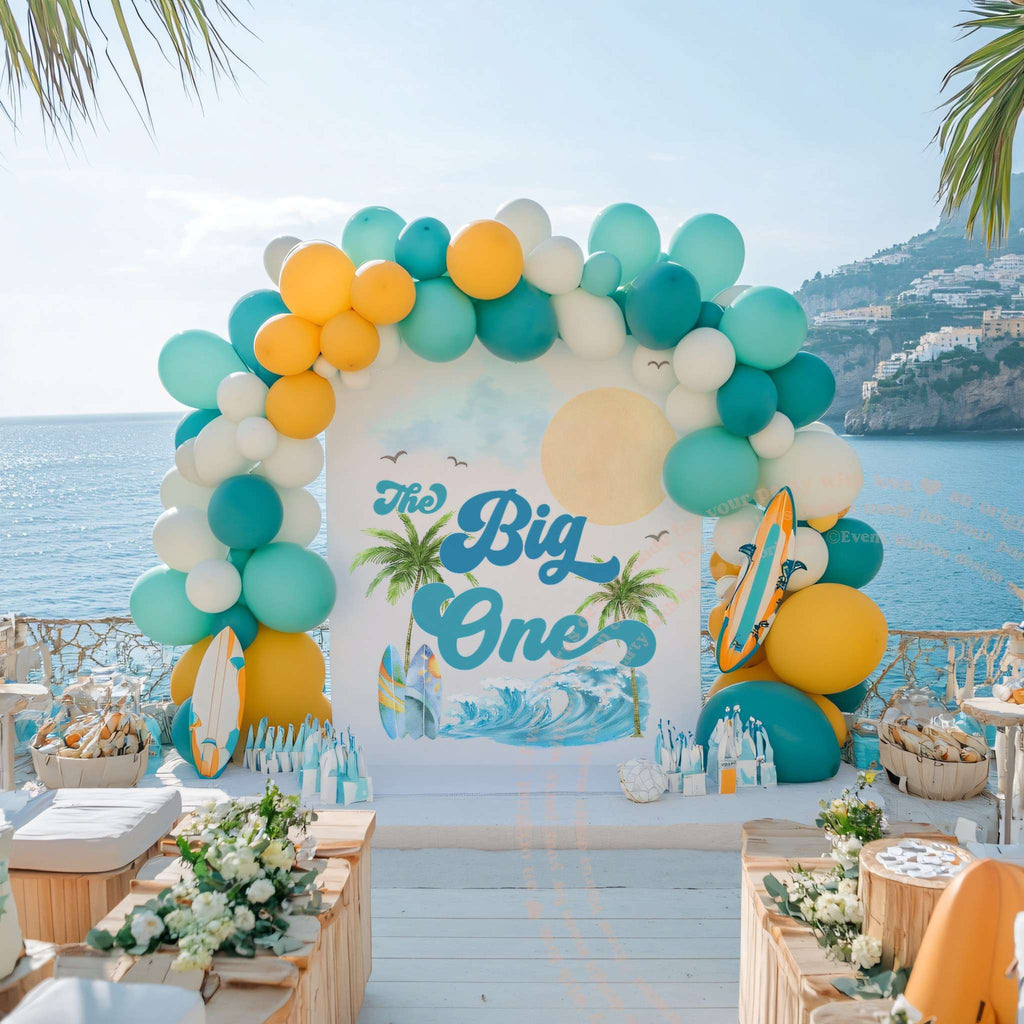 The Big One beach backdrop on a deck with an ocean view and balloon garland.