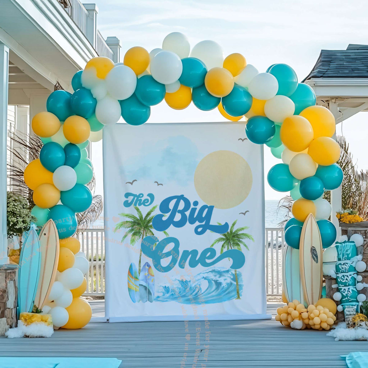 Palm tree surf backdrop in a teal and yellow balloon arch with surfboards.