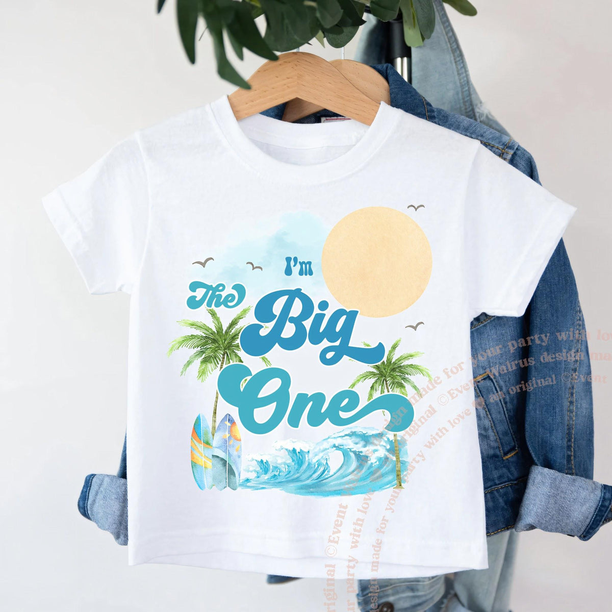 White I'm The Big One toddler shirt with palms and a wave on a wooden hanger.