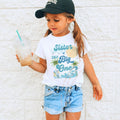 Girl in a ball cap wearing a white Sister of The Big One palm tree tee.
