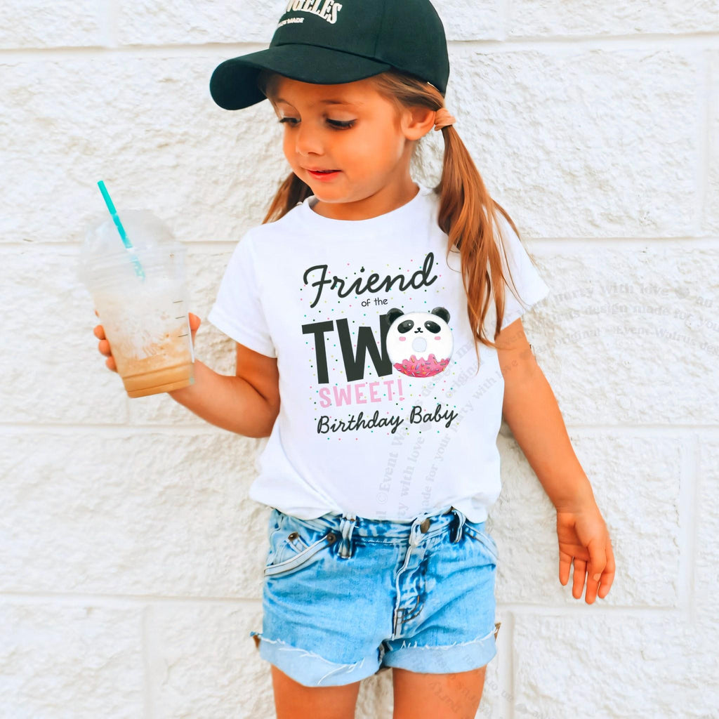 Girl in a ball cap holding a drink in a white Friend of the Two Sweet shirt.