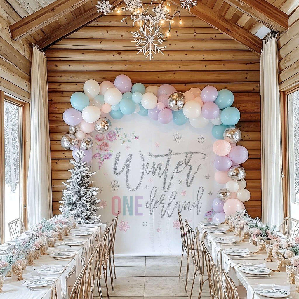 Pastel winter onederland backdrop in a log cabin dining room with a long party table.