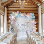 Pastel winter onederland backdrop in a log cabin dining room with a long party table.