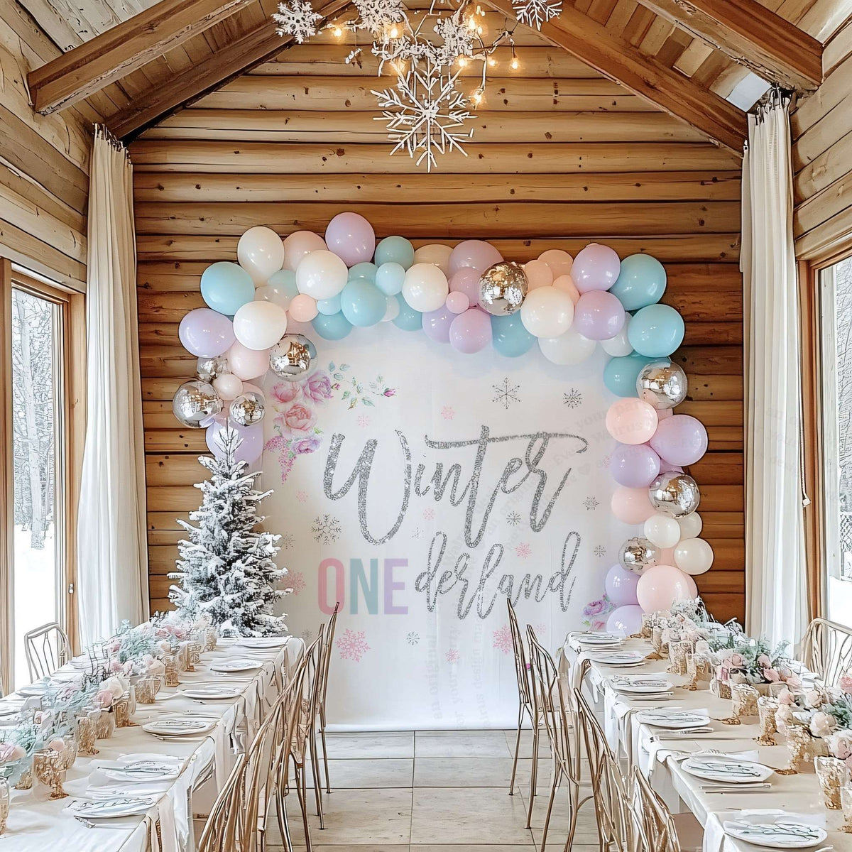 Pastel winter onederland backdrop in a log cabin dining room with a long party table.