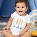 Smiling baby in a white I'm The Big One bodysuit with three pastel surfboards.