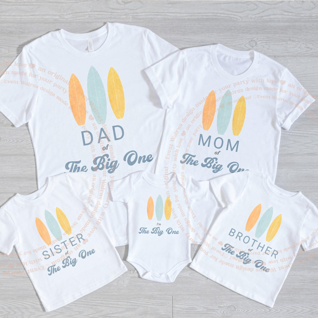White I'm The Big One bodysuit laid flat with the family's surfboard shirts.