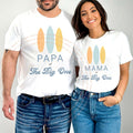 Couple in white Papa and Mama of The Big One shirts with three pastel surfboards.