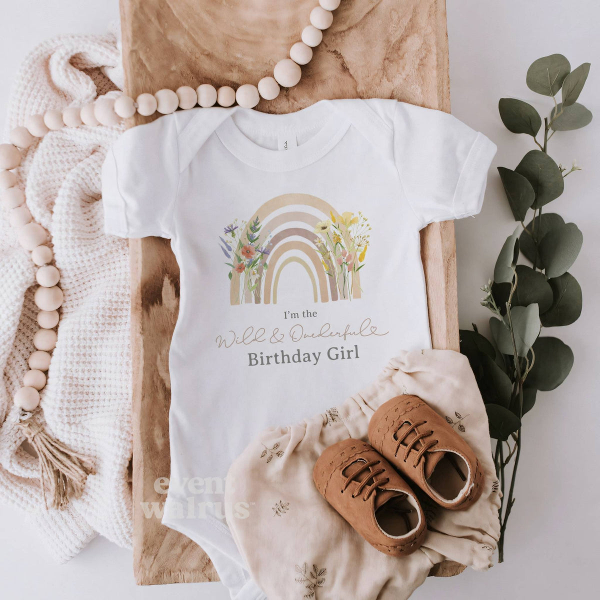 White I'm the Wild and Onederful Birthday Girl bodysuit with a pastel rainbow, laid flat.