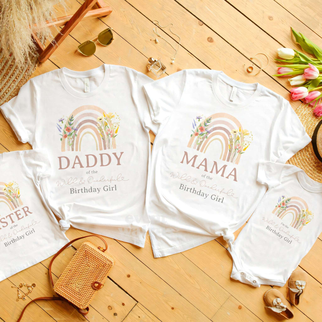 White Sister shirt beside Daddy and Mama rainbow shirts on a wood floor.