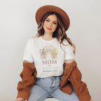 Woman in a brown hat wearing a white Mom shirt with a wildflower rainbow.