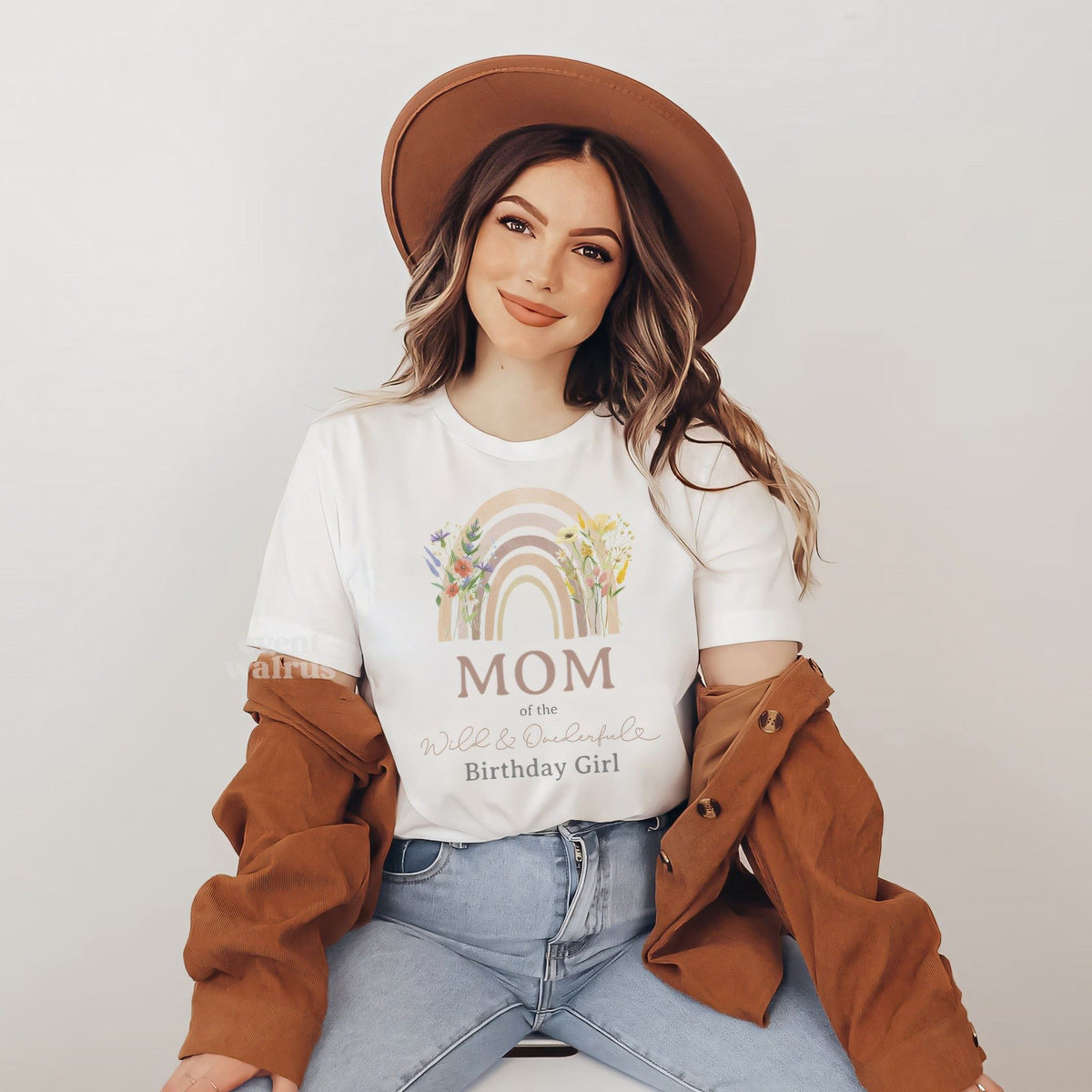 Woman in a brown hat wearing a white Mom shirt with a wildflower rainbow.
